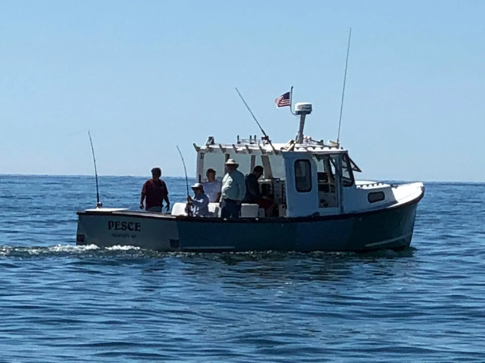 A group of friends fishing aboard the PESCE on a calm Cape Cod day